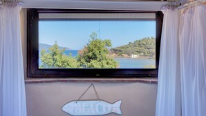 A window with a view of a lake, trees, and hills. - Agriresort Galenzana (Campo nell'Elba)