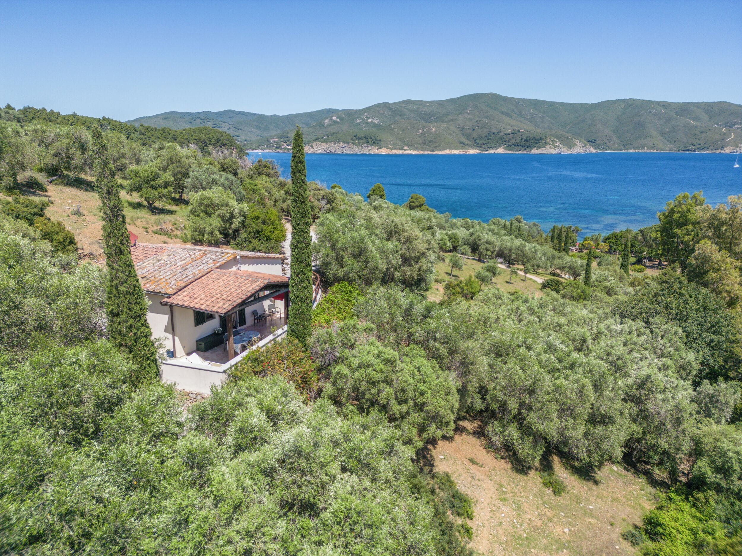 Ein Haus mit Ziegeldach, umgeben von üppiger Vegetation und freiem Blick auf das Meer.