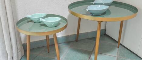 Two glass-top tables with wooden legs, each with a light blue bowl on top.