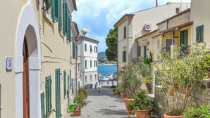 A narrow street with buildings on either side, potted plants, and a clear sky. - Agriresort Galenzana (Campo nell'Elba)