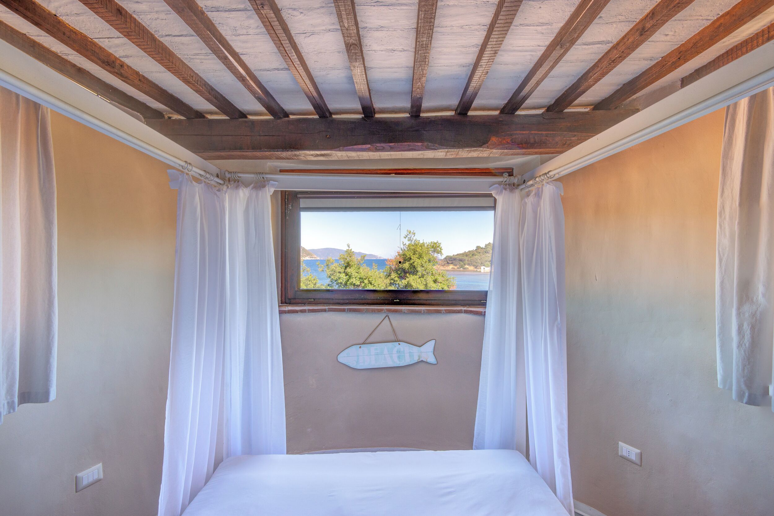 Un dormitorio con cama, ventana con vistas y decoración de pez en la pared.