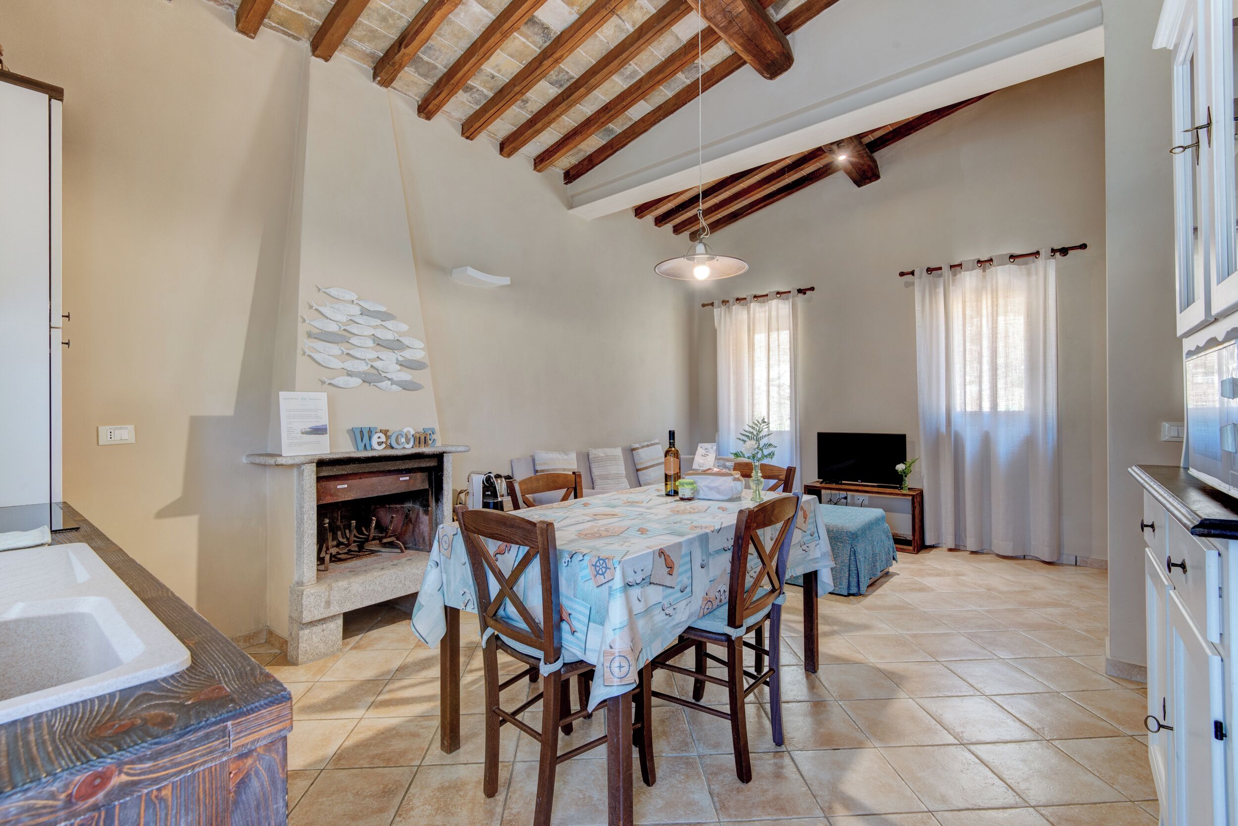 Un coin repas avec une table dressée pour quatre personnes, une cheminée et un téléviseur.