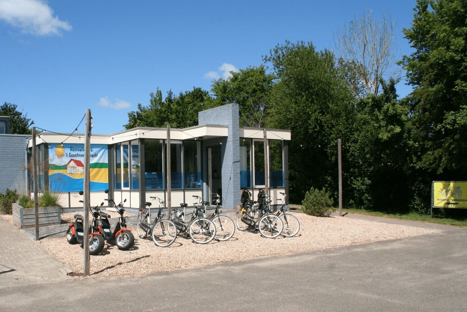 Ein Gebäude mit Glasfassade, Fahrräder vor der Tür und ein Banner mit Text.