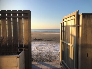 A wooden beach gate leading to a sandy beach with a clear view of the ocean. - Maritime-style vacation home with private garden (Warmenhuizen)