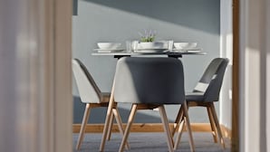 Ein Essbereich mit einem runden Tisch, zwei grauen Stühlen und einem kleinen Blumentopf.