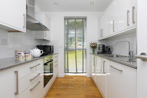 Eine moderne Küche mit weißen Schränken, einer Granitabdeckung, einem Backofen und einem Fenster mit Jalousien.
