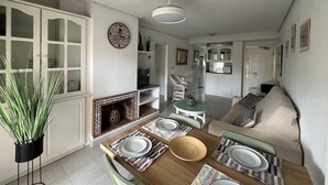 En matplats med ett träbord för fyra personer, en öppen spis och ett kök i bakgrunden.