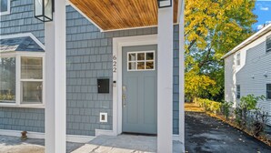 A house with a grey siding exterior, a blue door, and a stone-paved entrance.