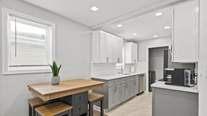 A modern kitchen with grey cabinets, a wooden table, and a potted plant.