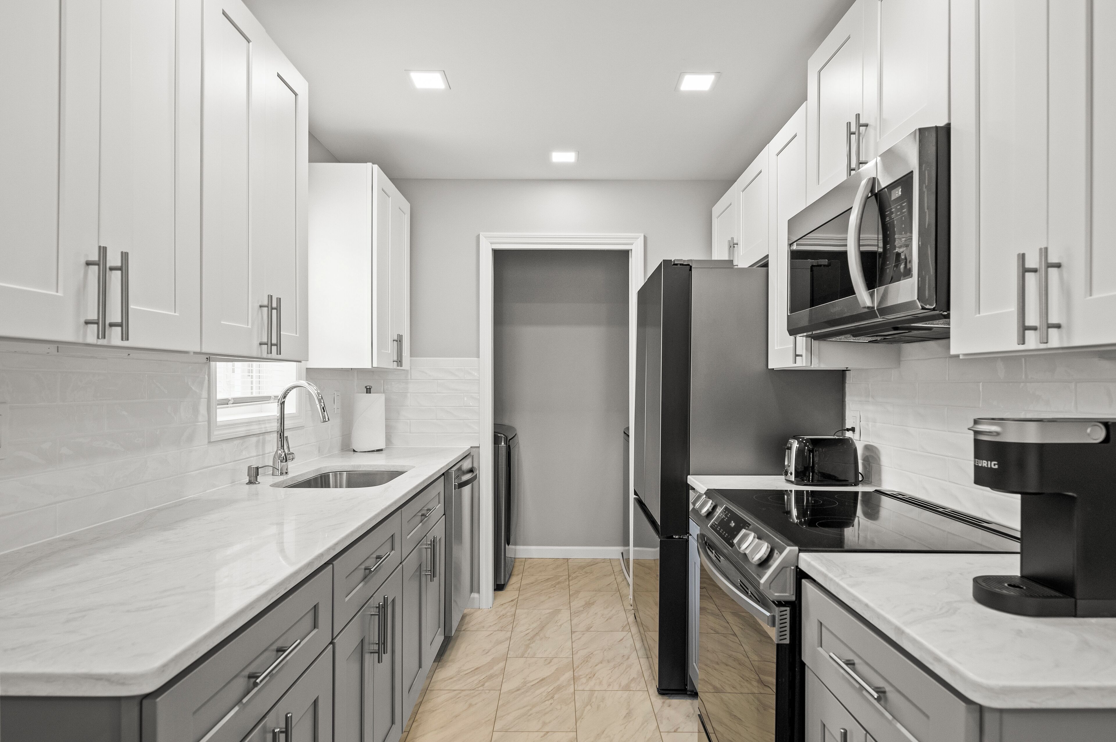 Una cocina moderna con armarios blancos, electrodomésticos de acero inoxidable y encimera de mármol.