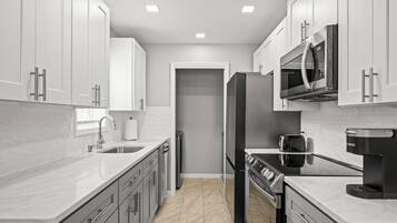 Una cocina moderna con armarios blancos, electrodomésticos de acero inoxidable y encimera de mármol.