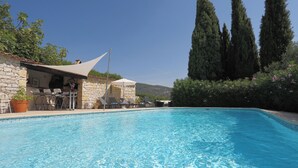 Una piscina amb un edifici de pedra i zona d'estar a l'aire lliure.