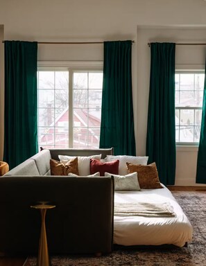 A bedroom with a bed, a sofa, and curtains.