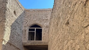 An arched doorway leading into a building with a rustic, earthen texture.