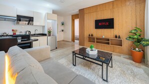 Ein modernes Wohnzimmer mit einer Couch, einem Couchtisch und einem an einer Holzwand befestigten Fernseher.