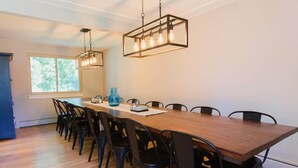 A dining area with a long wooden table, black chairs, and two pendant lights.