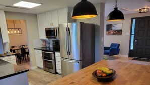 A modern kitchen with stainless steel appliances, a wooden island, and pendant lighting.