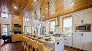 Una cocina amplia con techo de madera, armarios blancos y una isla grande con taburetes de bar.
