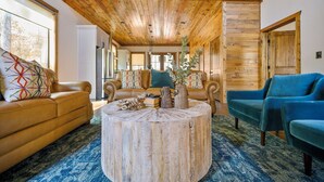 Un salón comedor amplio con techo alto, paredes de madera y un ventanal grande.