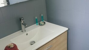 Une salle de bain avec un lavabo blanc, un meuble-lavabo en bois et un miroir au-dessus.