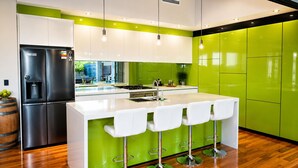 A modern kitchen with a central island, stainless steel appliances, and green cabinetry.