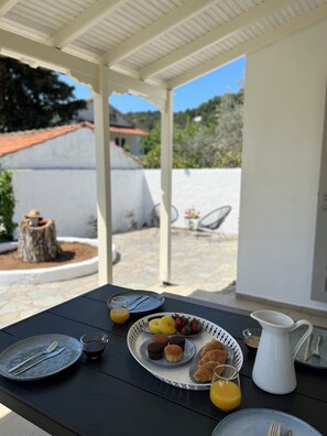 Un espacio de comedor al aire libre con una mesa preparada para el desayuno, incluyendo platos, cubiertos y una jarra.