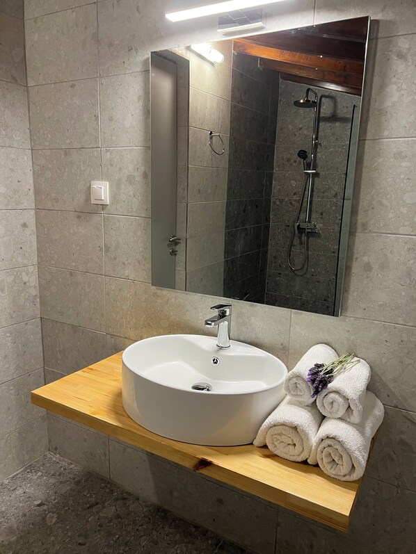Un baño con lavamanos blanco, espejo y ducha.