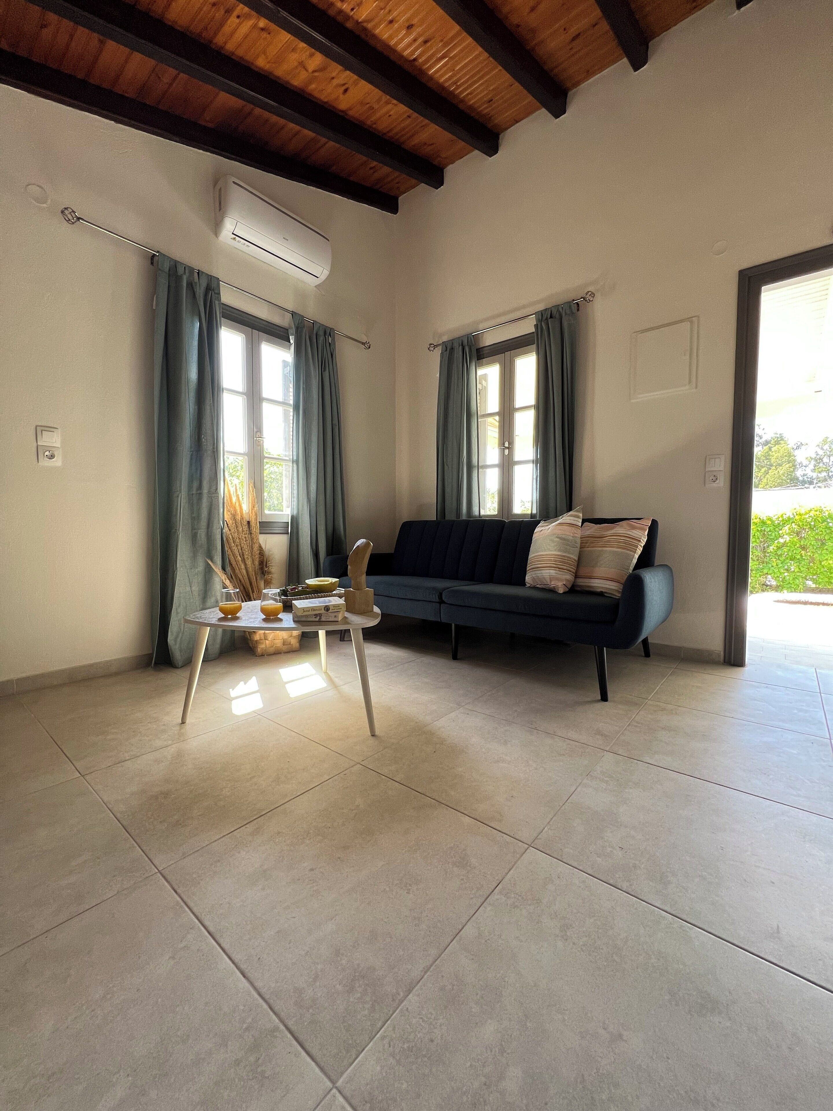 A living room with a sofa, a coffee table, and a window with curtains.