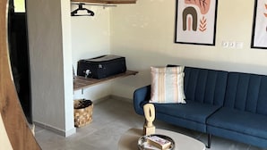 Una sala de estar con un sofá azul, una mesa de centro, una escalera de madera y dos cuadros en la pared.