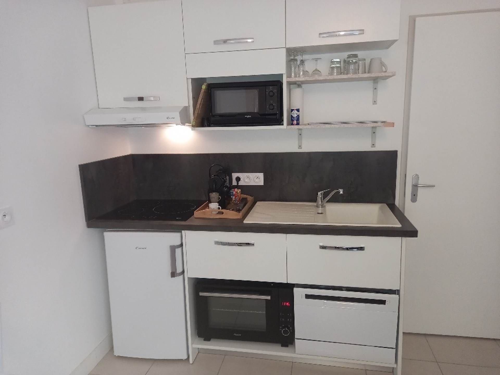 A compact kitchen with a microwave, oven, and sink.