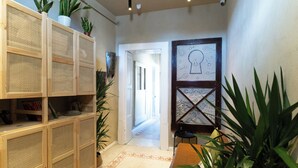 A hallway with a wooden shelving unit, a patterned door, and potted plants. - HOPESTEL Secret Garden Napoli (Naples)