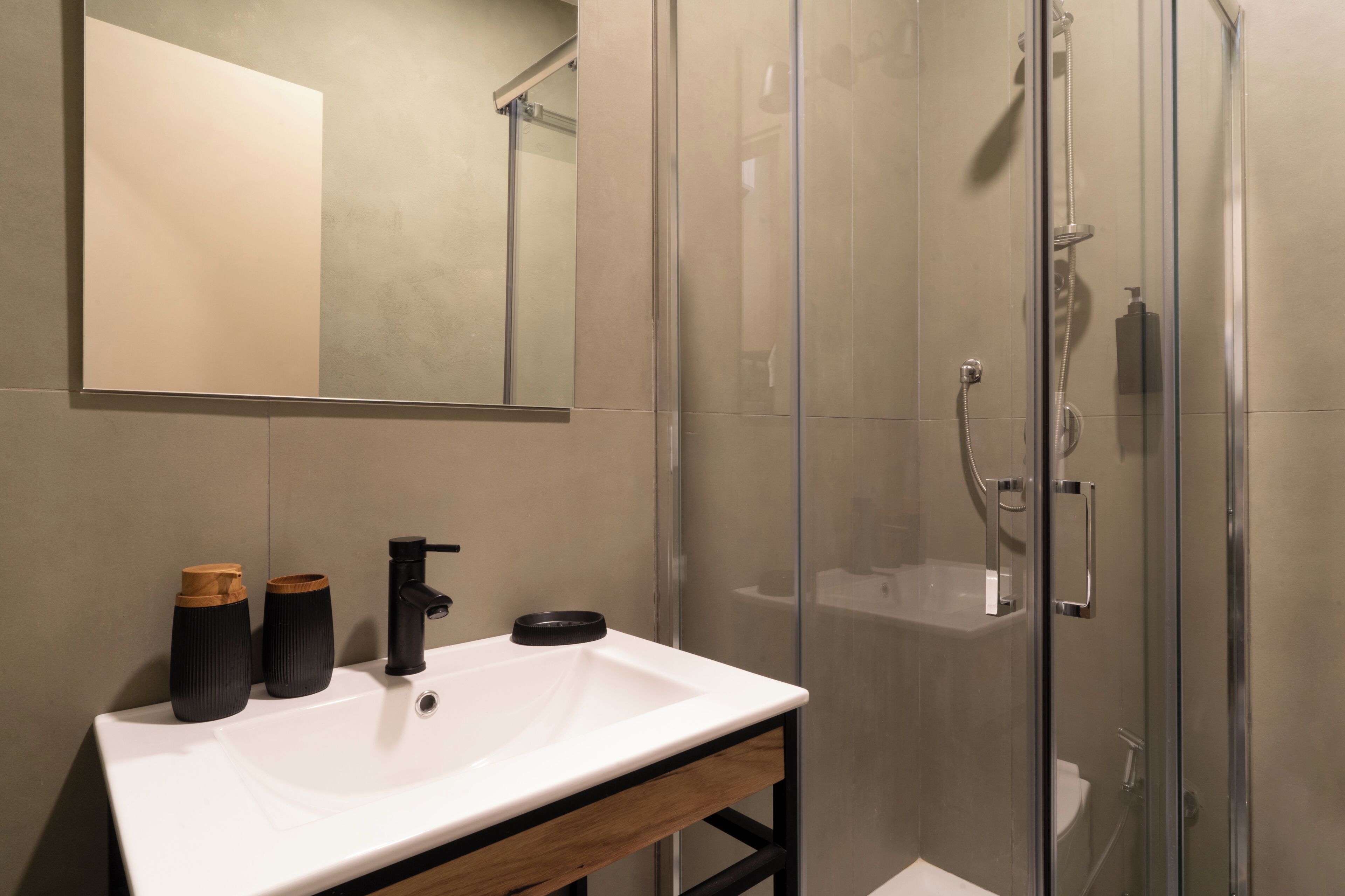 A modern bathroom with a white sink, black faucet, and two black vases.