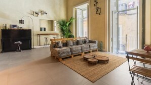 A spacious living area with a sofa set, a dining table, and a piano. - HOPESTEL Secret Garden Napoli (Naples)