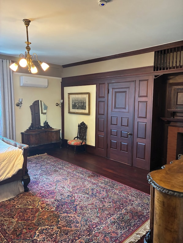 A room with a large bed, a wooden floor, a patterned rug, a chandelier, a wardrobe, and a framed picture on the wall. - Alden Villa (Lebanon)