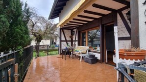 Un patio techado con un banco de madera, una mesa y plantas en macetas.