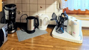Una cocina abierta con armarios de madera, una cafetera, un hervidor y una tostadora en la encimera.