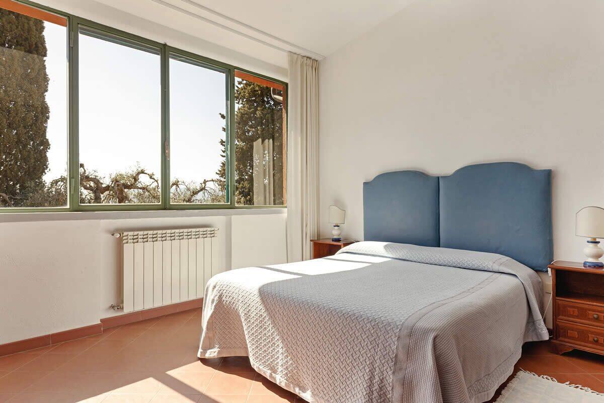 Een slaapkamer met een bed, nachtkastje, raam en radiator.