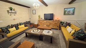 Een woonkamer met een zithoek, een televisie en een kast.