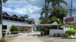 A beach club entrance with a stop sign, palm trees, and a building with a balcony.