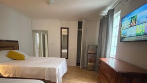 A hotel room with two beds, a wooden dresser, a television, and a wardrobe.
