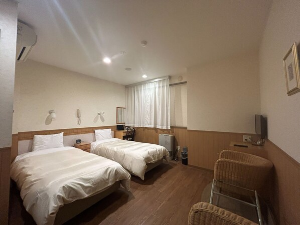A hotel room with two beds, a desk, a chair, a television, and a window with curtains. - Lasting Hotel (Kushiro)