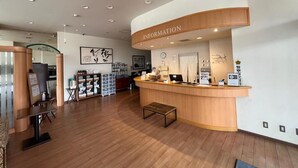 A reception area with a wooden counter, a clock, and a sign labeled "INFORMATION". - Lasting Hotel (Kushiro)
