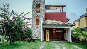 A modern house with a stone tower, a red upper section, and a covered entrance. - Summerville #159 - House With Pool by Carpediem (Caucaia)