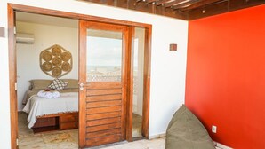 A room with a bed, a wooden door, a red wall, and a view through the door. - Summerville #159 - House With Pool by Carpediem (Caucaia)