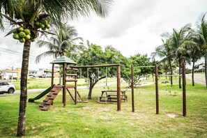 A playground with swings, a slide, and a picnic table. - Summerville #159 - House With Pool by Carpediem (Caucaia)
