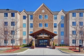 A multi-story building with a stone facade, a central entrance with a covered walkway, and multiple windows.