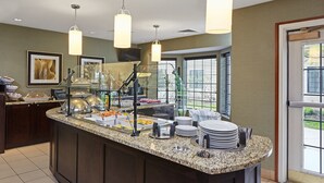 Ein Frühstücksbuffet mit verschiedenen Speisen, darunter Obst und Gebäck, sowie eine Stapel Teller.