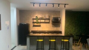 Una cocina moderna con una isla central, taburetes de bar, un refrigerador y un microondas.