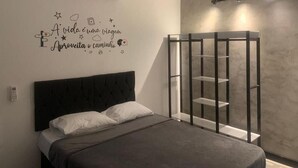 Un dormitorio con cama, aire acondicionado de pared, una frase motivacional y una estantería.