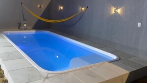 Una piscina con una hamaca amarilla, rodeada por muros con iluminación integrada.